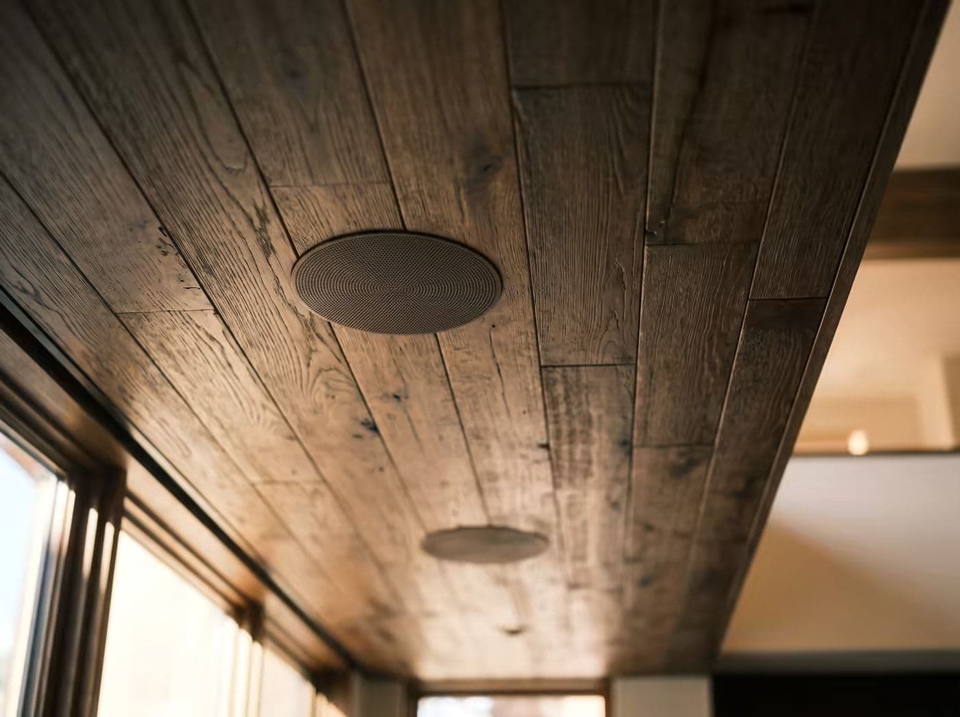 Ceiling speaker grilles finished flush into a wood plank ceiling