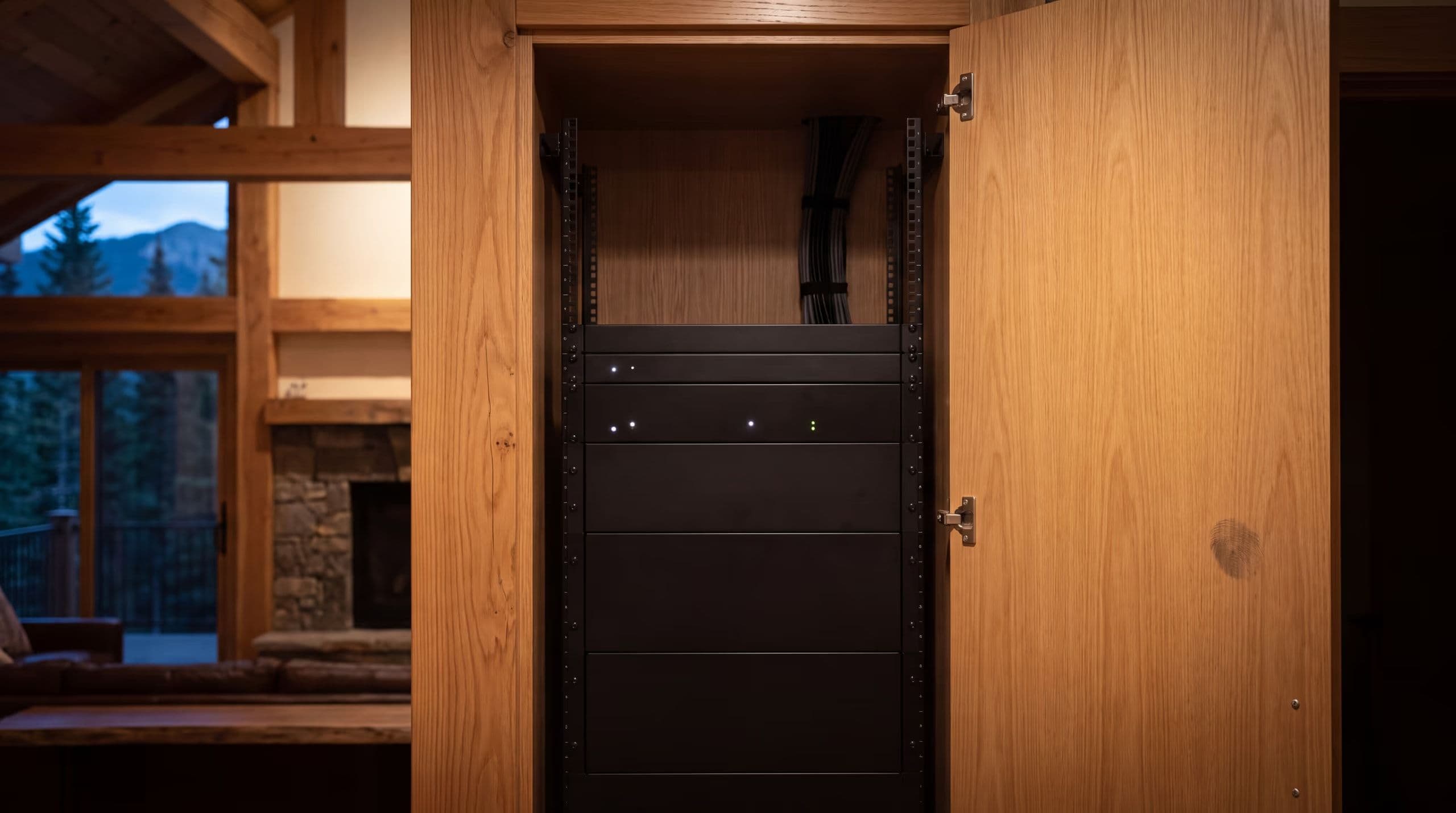 An equipment rack behind an open flush cabinet door, its front face solid and clear of cabling because every connection is made at the rear